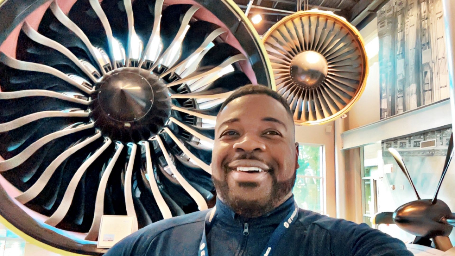 Willy Valcin posed in front of GE Aerospace jet engine